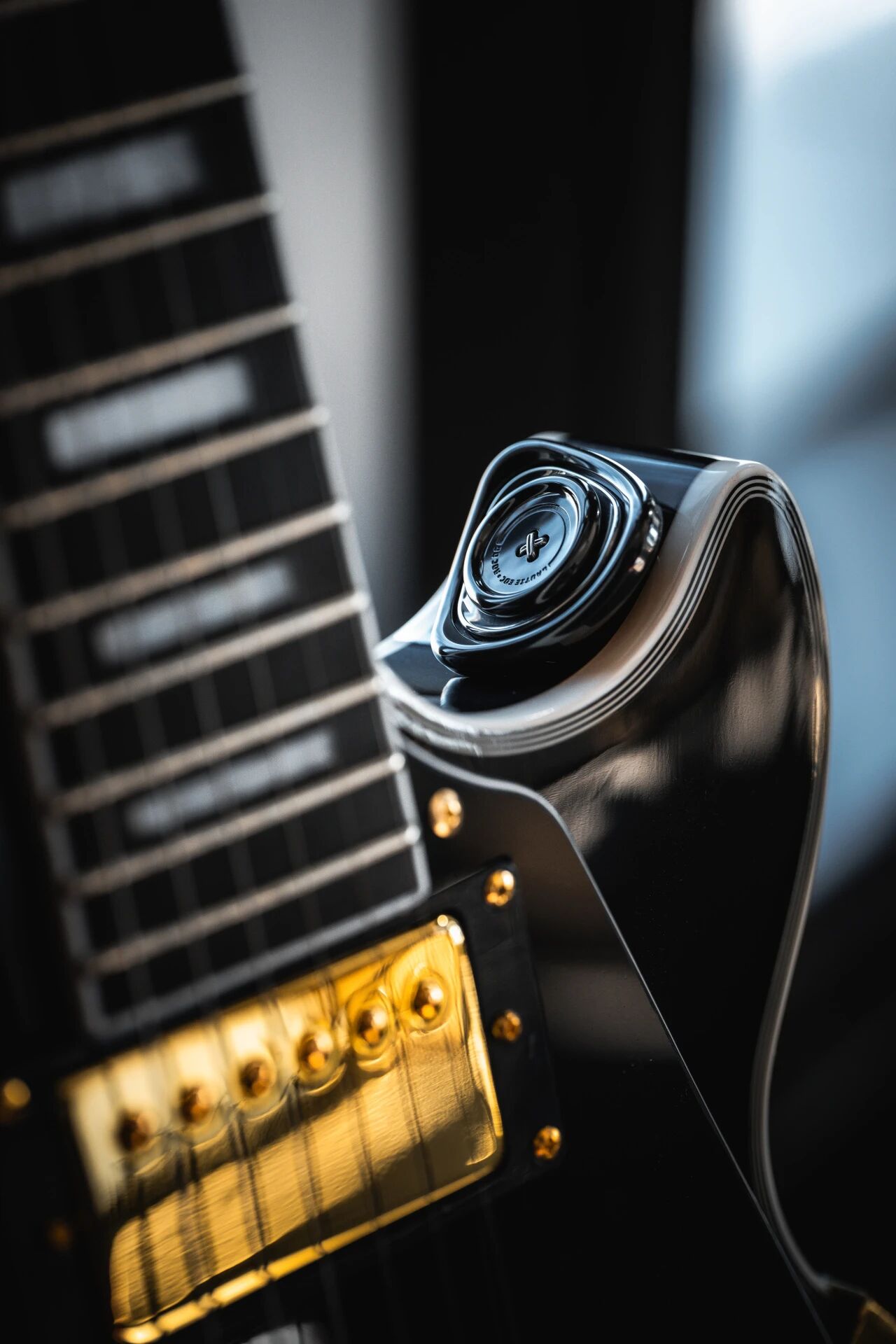 LAUTIE ROC OG titanium baked-blue dark variant resting on Gibson Les Paul guitar headstock brass fretboard