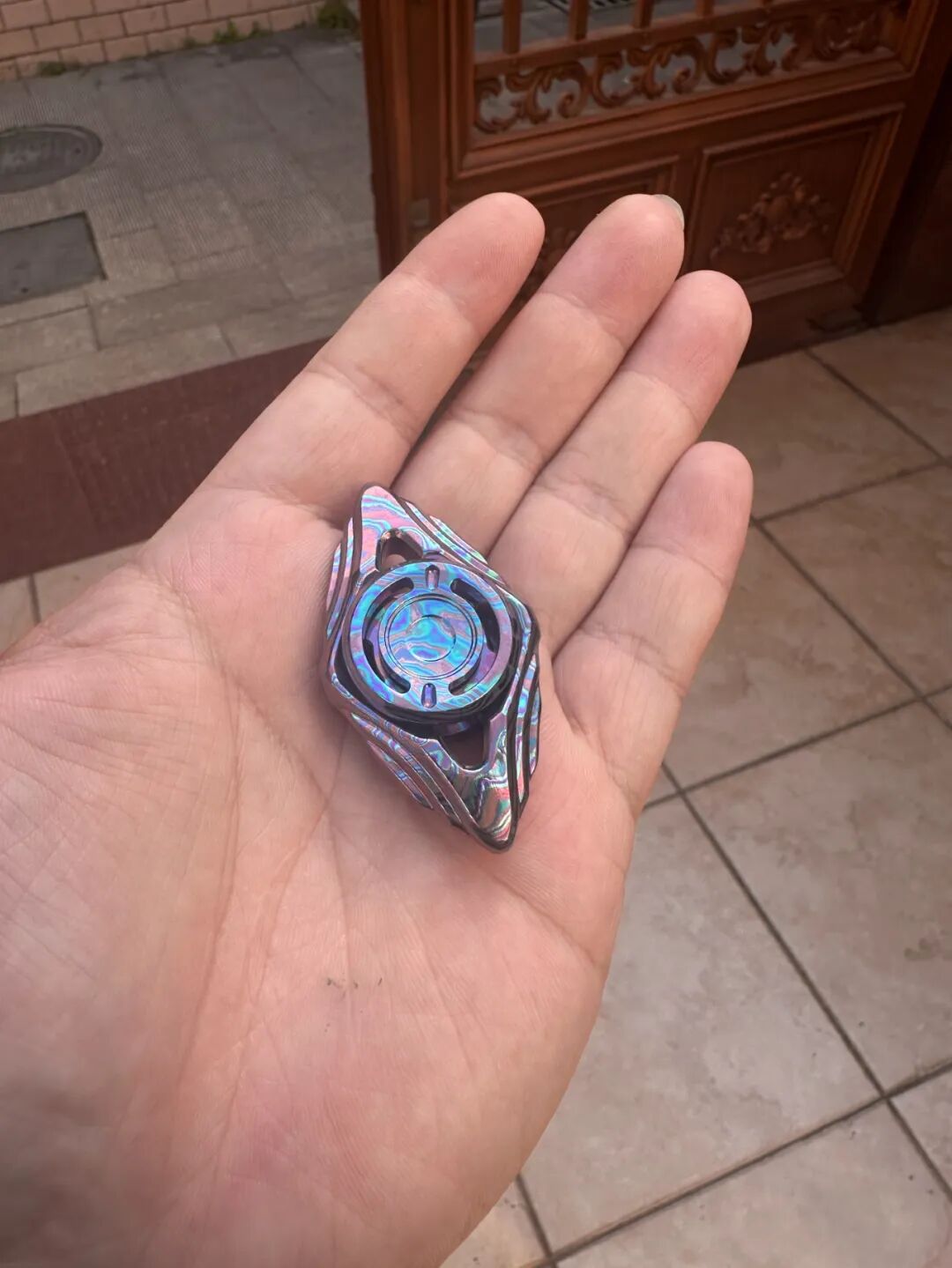 A candy-blue Zircuti Shitu in a palm, with pale blue and lavender patterns around the central button