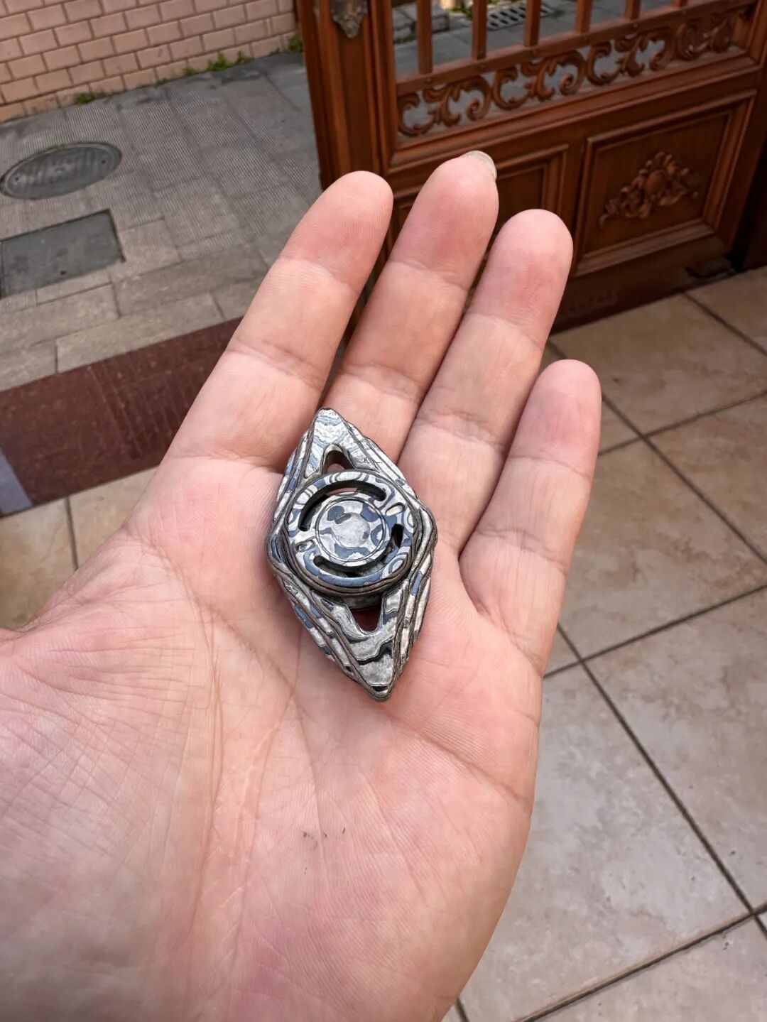 A black-and-white Zircuti Shitu in a palm, with contrasting bands along its ends and central button