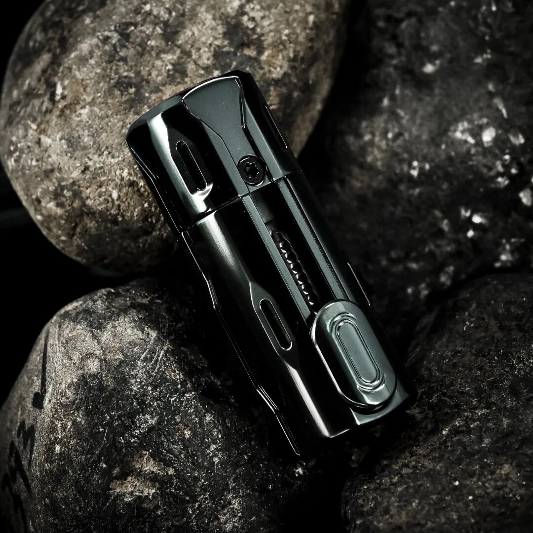 A glossy black Phase 1.5 rests between rocks, with bright reflections following the edges of its body.