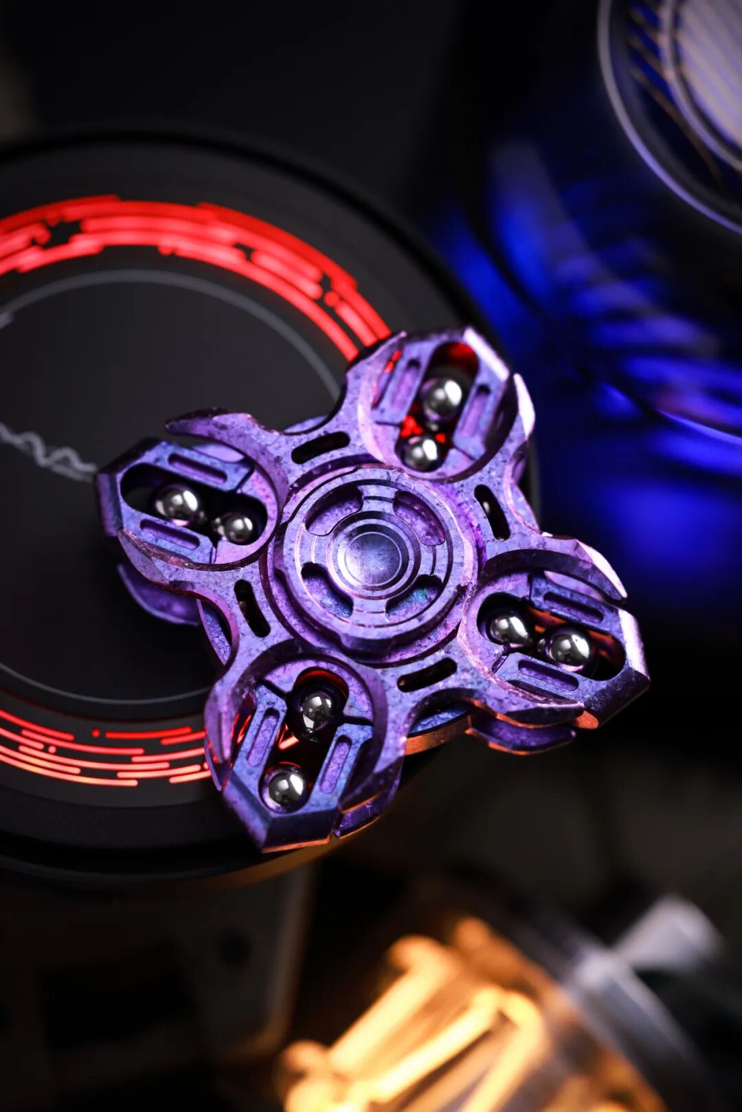 A purple crystallized zirconium Oracle spinner on a dark stand, with spherical components around its perimeter