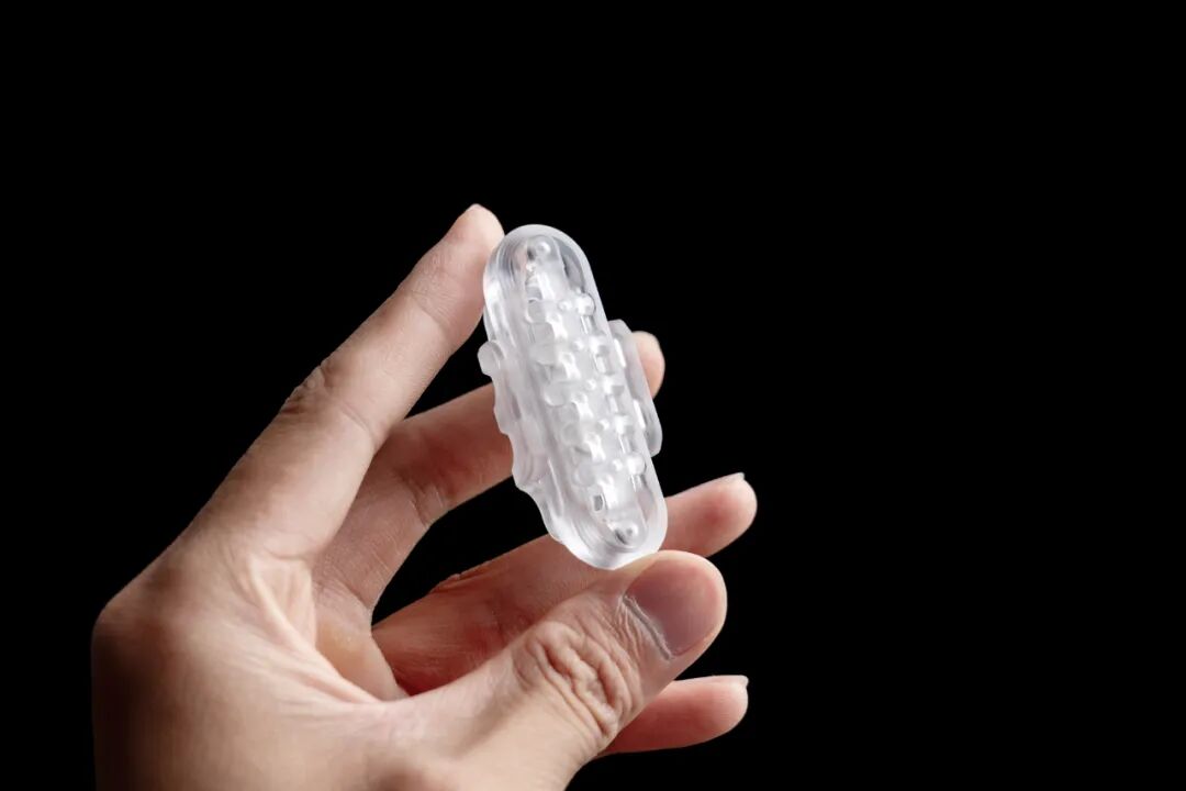 A transparent PC Ganggu held in a hand, with internal outlines visible through the exterior