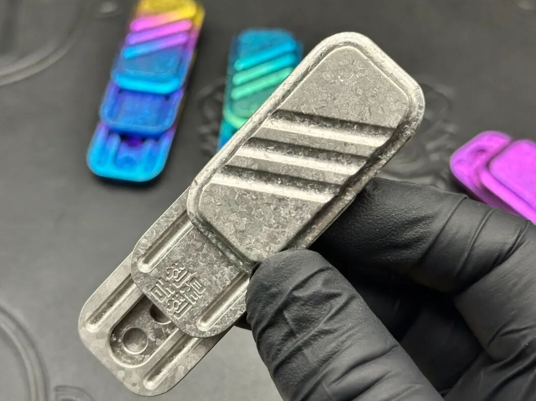 A gloved hand holding a pale silver-coloured crystallized zirconium Lucky Candy, with fine surface texture visible