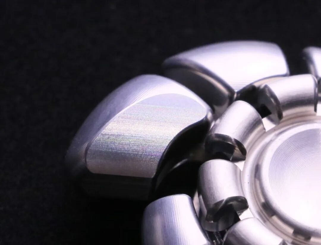 Close-up of natural-colour zirconium Yingwuluo showing fine, continuous machining marks along a curved surface.