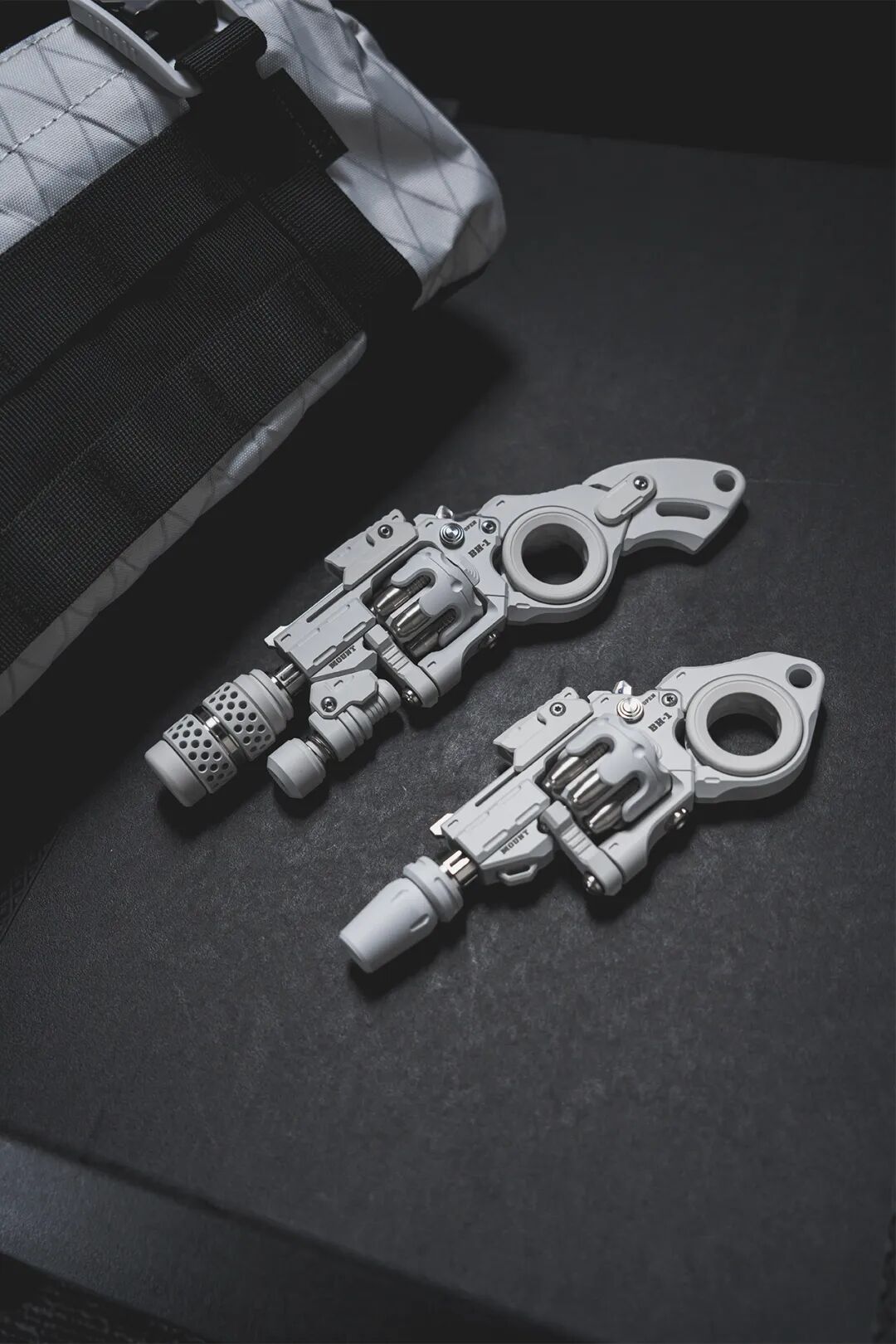Two white Breaker Howitzer fidget models of different lengths on dark fabric