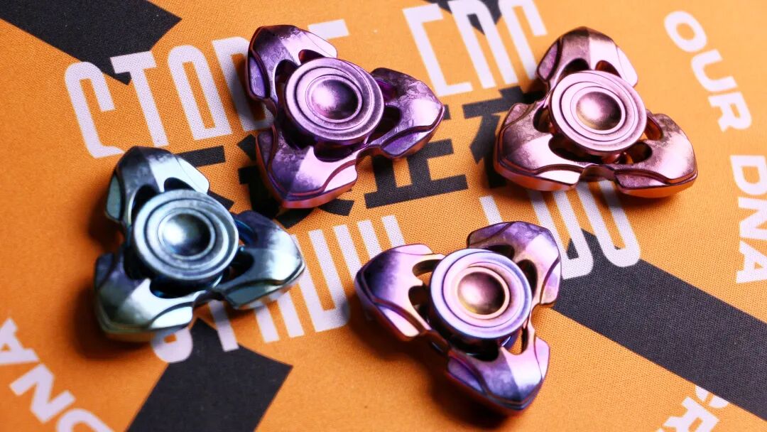 Four differently coloured crystallized zirconium Toothless spinners on an orange mat